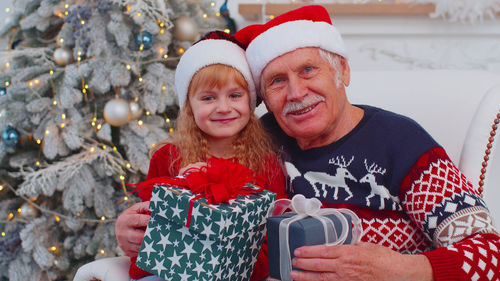 Portrait of smiling grandfather and granddaughter holding christmas gift
