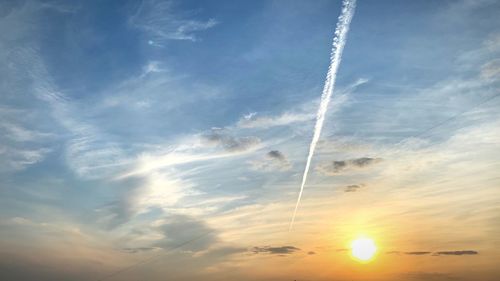 Low angle view of vapor trail in sky during sunset