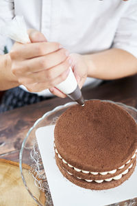 Midsection of person holding cake on table