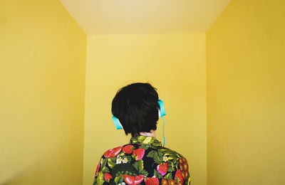 Rear view of woman against yellow background