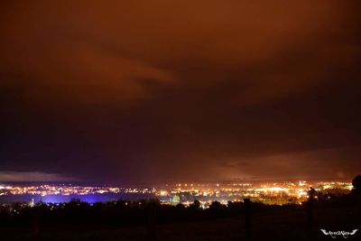 Illuminated city against sky at night