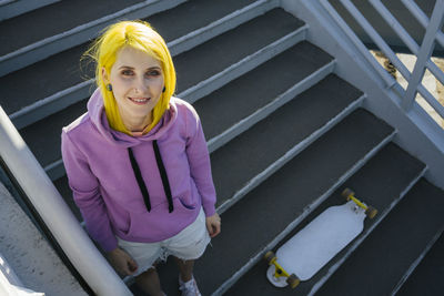 Portrait of a smiling young woman standing against railing