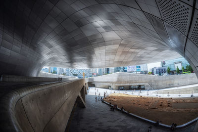 Empty illuminated tunnel with buildings in background