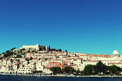 Buildings in city against clear blue sky