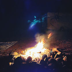 Bonfire by sea against sky at night