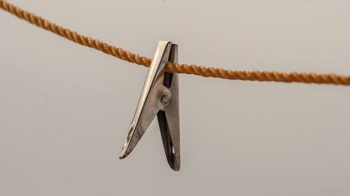 Low angle view of clothespins on rope against white background