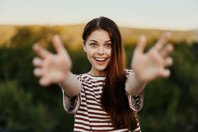 Portrait of smiling young woman standing against trees