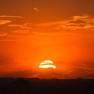 Silhouette trees against dramatic sky during sunset