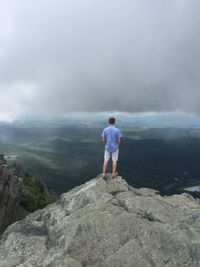 Rear view of man looking at mountain against cloudy sky