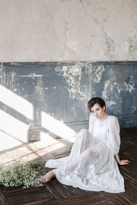 Woman sitting on floor against white wall