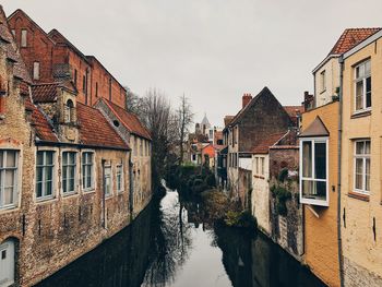 Canal amidst buildings in town against sky