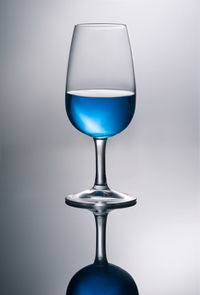 Blue wine in glass against gray background