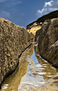 Scenic view of stream amidst mountains against sky