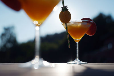 Two orange peach cocktails in glass with ice cubes and straw