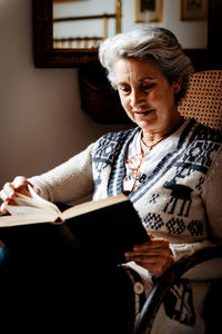 Elderly woman reading by window with enthusiasm