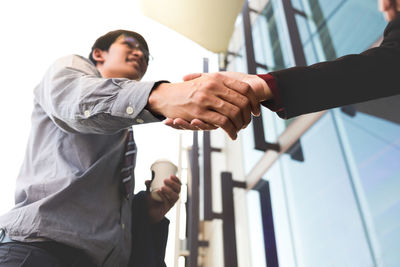 Low angle view of business people shaking hands against building