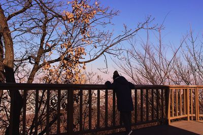 Full length of woman standing by railing against clear sky