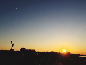 Silhouette people standing against clear sky during sunset