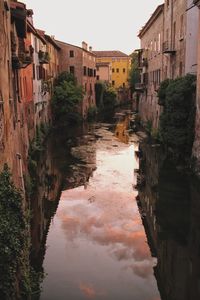 Canal amidst buildings in town against sky