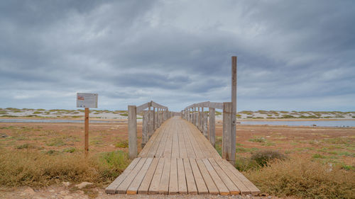 View of wooden walkway on field against sky