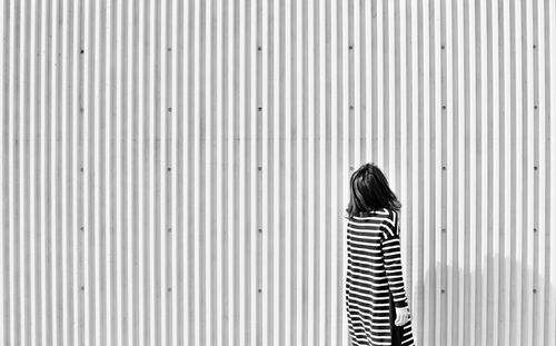 Rear view of woman standing in front of corrugated iron
