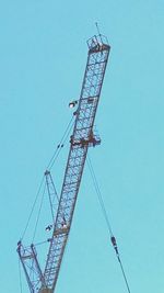 Low angle view of crane against clear blue sky