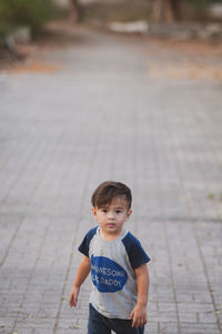 Portrait of cute boy standing on footpath