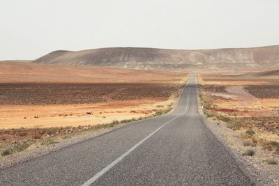 Desert road leading towards mountain