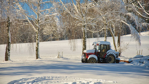 Snow covered field by trees during winter