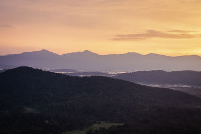 Mountains range misty shadow with dramatic colorful sunset sky at dusk from flat angle