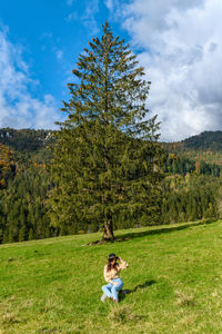 Woman sitting on field against sky