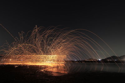 Firework display over river against sky at night