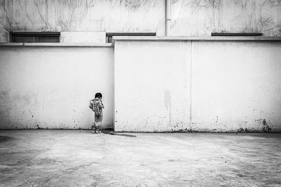 Woman standing by building against wall