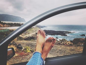 Low section of woman with feet up on car door