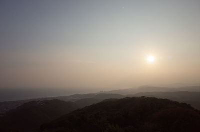 Sun shining through clouds over mountain