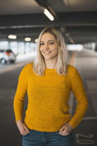 Portrait of smiling young woman standing in underground parking lot