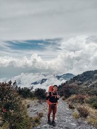 Rear view of man standing on mountain against sky