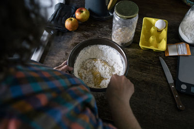 High angle view of woman mixing ingredient in flour on kitchen counter