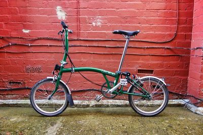 Bicycle parked against brick wall