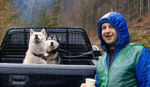 Traveler with siberian tow beautiful husky dog in the wagon car. person with dog in the forset