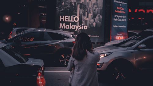 Rear view of woman standing on city street at night