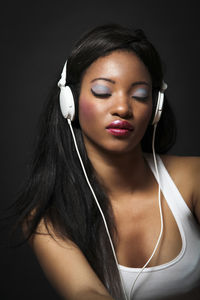 Woman listening music against black background