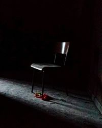 Empty chair on table against dark background