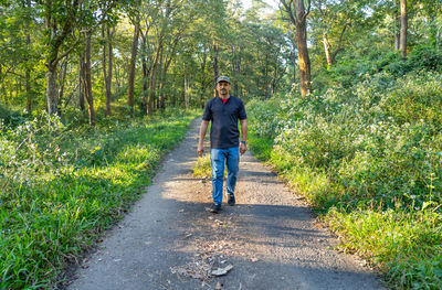 Rear view of man walking on footpath in forest
