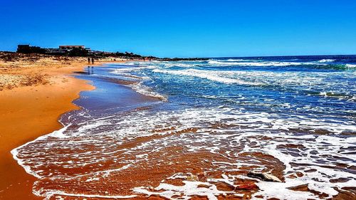 Scenic view of beach against clear blue sky