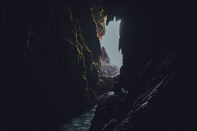 Low angle view of silhouette people on rock against sky