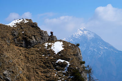 Low angle view of man standing on rock against sky