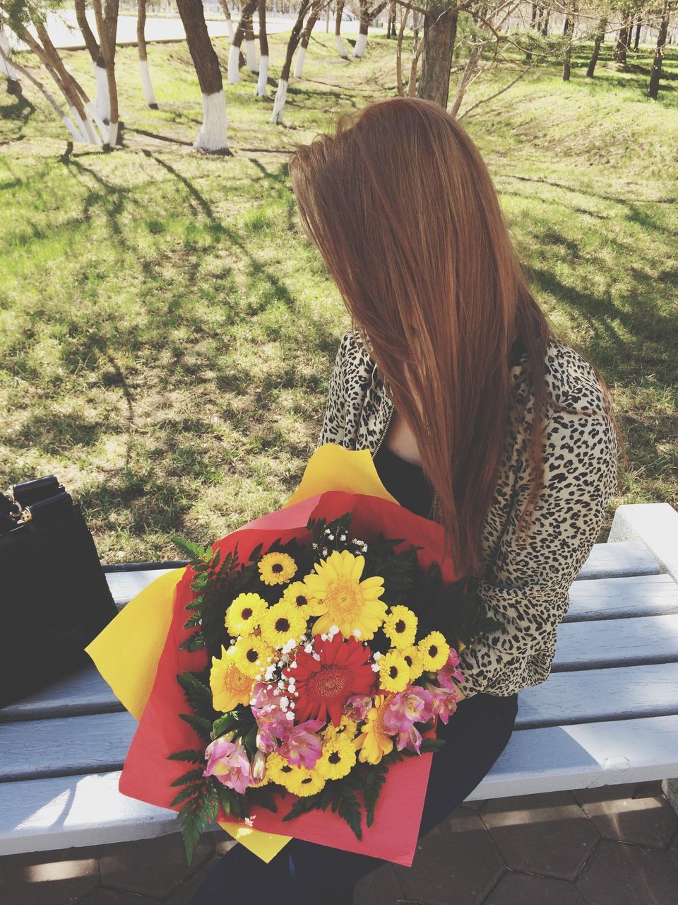 flower, park - man made space, tree, petal, fragility, growth, tree trunk, day, yellow, nature, focus on foreground, flower head, freshness, outdoors, long hair, lifestyles, leisure activity, sunlight