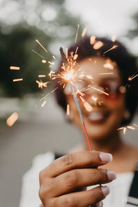 Midsection of woman holding sparkler at night