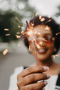 Close-up of woman hand holding lit sparkler